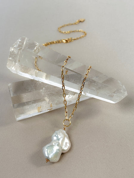 styled image of baroque pearl pendnat draped over crytal spikes against a neutral gray background